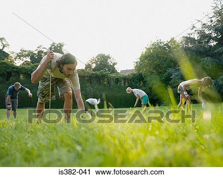 Stock Image - Golfers searching in grass. Fotosearch