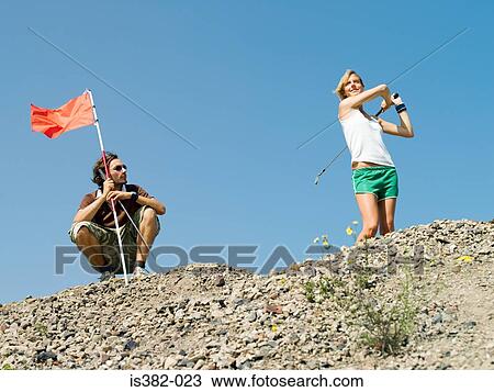 Stock Image - Man and woman playing golf. Fotosearch
