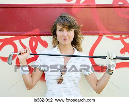 Stock Image - Woman holding golf club. Fotosearch