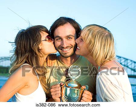 Women kissing man with trophy View Large Photo Image Stock Photograph - Women kissing man with trophy. Fotosearch
