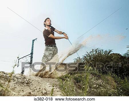 Young man playing golf on wasteland View Large Photo Image Stock Photo - Young man playing golf on wasteland. Fotosearch