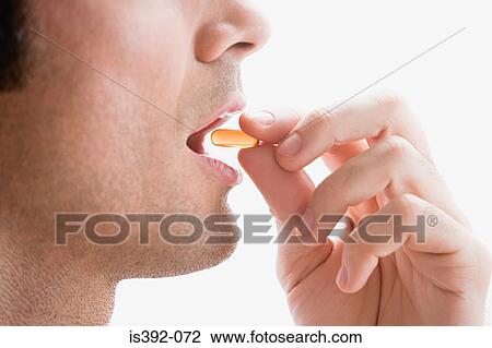 Stock Image - Man taking a vitamin pill. Fotosearch