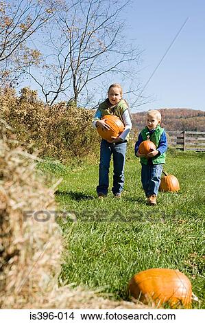 Boy and girl carrying pumpkins View Large Photo Image Picture - Boy and girl carrying pumpkins. Fotosearch