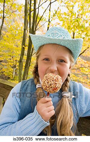Girl eating a toffee apple View Large Photo Image Stock Photography - Girl eating a toffee apple. Fotosearch