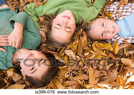Girls lying on leaves View Large Photo Image Stock Photograph - Girls lying on leaves. Fotosearch
