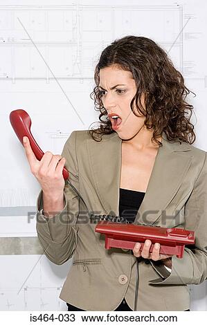 Stock Image - Shocked woman looking at telephone. Fotosearch