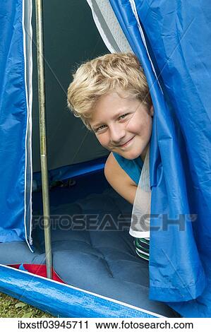 Stock Image - "A boy, 10 years, looking out of his tent". Fotosearch