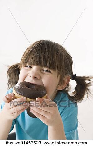 A girl biting into a donut with pleasure View Large Photo Image Stock Image - A girl biting into a donut with pleasure. Fotosearch