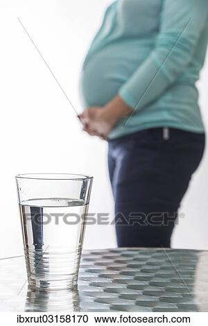 "A glass water is resting on a table, pregnant woman, 8 months, at back" View Large Photo Image Stock Image - "A glass water is resting on a table, pregnant woman, 8 months, at back". Fotosearch