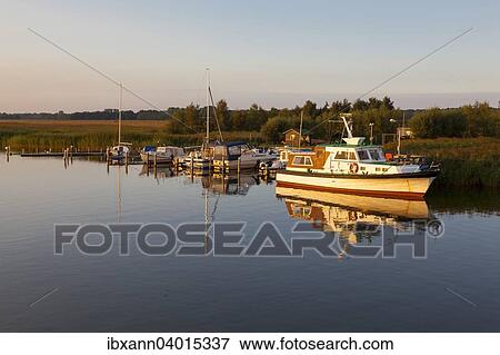 "A small motorboat anchored at a landing stage on the Bodden lagoon, evening mood, Zingst, Fischland-Zingst, Mecklenburg-Western Pomerania, Germany, Europe" View Large Photo Image Stock Photo - "A small motorboat anchored at a landing stage on the Bodden lagoon, evening mood, Zingst, Fischland-Zingst, Mecklenburg-Western Pomerania, Germany, Europe". Fotosearch