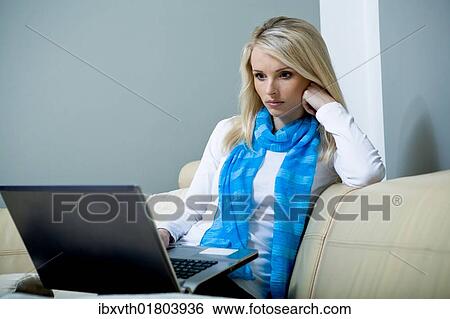 A young woman with a laptop on a sofa View Large Photo Image Stock Photograph - A young woman with a laptop on a sofa. Fotosearch