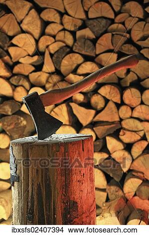 "Axe on a log, stacked firewood at the back" View Large Photo Image Picture - "Axe on a log, stacked firewood at the back". Fotosearch
