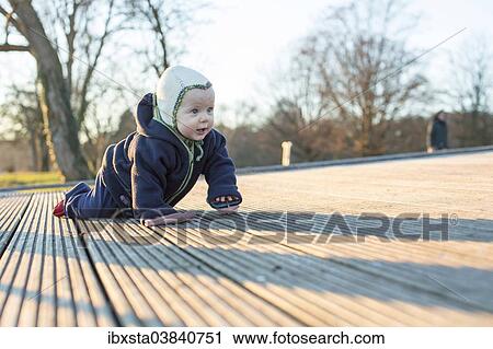 Stock Image - "Baby, 9 months, crawling over a wooden floor, Konstanz, Baden-Wurttemberg, Germany, Europe". Fotosearch