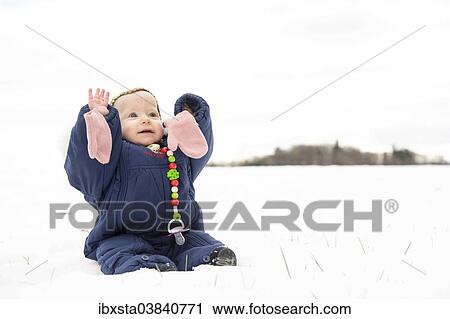 "Baby, 9 months, sitting with a snowsuit in the snow" View Large Photo Image Stock Image - "Baby, 9 months, sitting with a snowsuit in the snow". Fotosearch