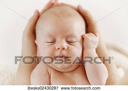 Stock Photo - "Baby girl, 3 months, being held by hands, portrait". Fotosearch