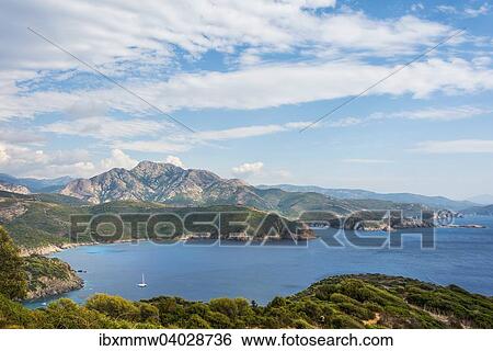 Stock Photograph - "Bay with a sailing boat, coastal and mountain scenery, Gulf of Porto, Corsica, France, Europe". Fotosearch