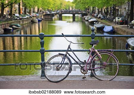 "Bicycle on a bridge crossing a canal in the historic city centre of Amsterdam, Holland, Netherlands, Europe" View Large Photo Image Stock Photo - "Bicycle on a bridge crossing a canal in the historic city centre of Amsterdam, Holland, Netherlands, Europe". Fotosearch