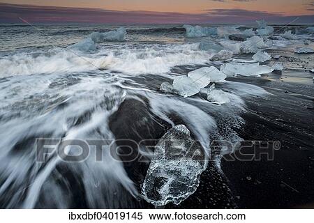 Stock Photography - "Blocks of ice on the black beach lapped by the sea, sunset, at Jokulsarlon Glacial Lagoon, Vatnajokull Glacier, Eastern Region, Iceland, Europe". Fotosearch