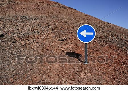 "Blue sign with a white arrow pointing left, on red lava, Lanzarote, Canary Islands, Spain, Europe" View Large Photo Image Picture - "Blue sign with a white arrow pointing left, on red lava, Lanzarote, Canary Islands, Spain, Europe". Fotosearch