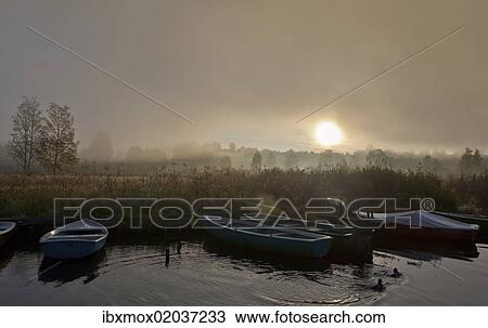 Stock Image - "Boats in the fog on Lake Staffelsee with the island of Woerth near Seehausen, Murnau, Upper Bavaria, Bavaria, Germany, Europe, PublicGround, Europe". Fotosearch