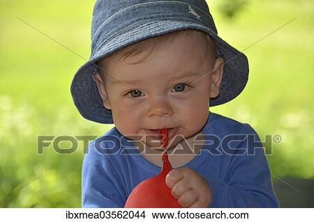 Picture - "Boy, 10 months, playing with a red balloon outdoors". Fotosearch