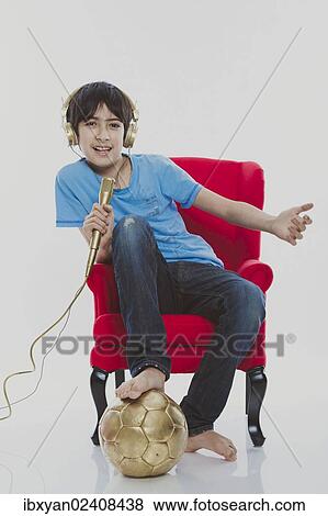 "Boy, 12, sitting on a red chair wearing golden headphones with a gold football and singing into a golden microphone" View Large Photo Image Stock Photo - "Boy, 12, sitting on a red chair wearing golden headphones with a gold football and singing into a golden microphone". Fotosearch