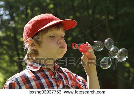 Stock Image - Boy blowing soap bubbles. Fotosearch