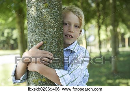 Boy hugging a tree trunk View Large Photo Image Stock Photograph - Boy hugging a tree trunk. Fotosearch