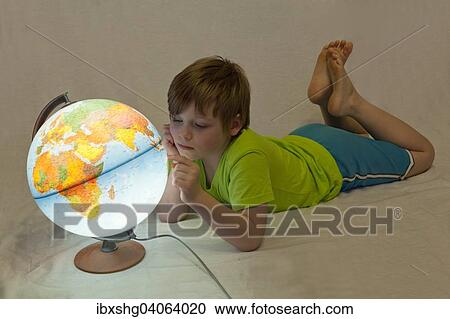 Stock Image - Boy looking at an illuminated globe. Fotosearch