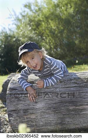"Boy, playing outdoors, on a tree trunk, portrait" View Large Photo Image Stock Image - "Boy, playing outdoors, on a tree trunk, portrait". Fotosearch