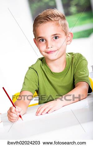Stock Image - Boy with a sketch-pad at a table. Fotosearch