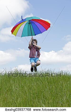 Boy with colorful umbrella jumping on meadow View Large Photo Image Stock Photo - Boy with colorful umbrella jumping on meadow. Fotosearch