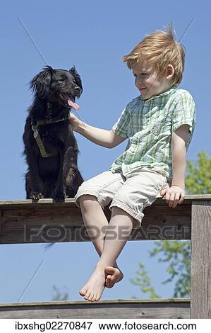 Stock Photo - Boy with dog sitting on a fence. Fotosearch