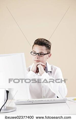 Boy working on a computer at his desk View Large Photo Image Stock Image - Boy working on a computer at his desk. Fotosearch