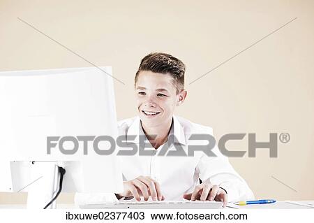 Stock Image - Boy working on a computer at his desk. Fotosearch