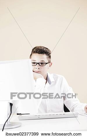 Boy working on a computer at his desk View Large Photo Image Stock Photo - Boy working on a computer at his desk. Fotosearch