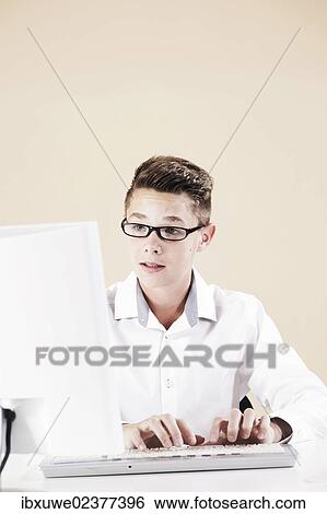 Boy working on a computer at his desk View Large Photo Image Stock Photograph - Boy working on a computer at his desk. Fotosearch