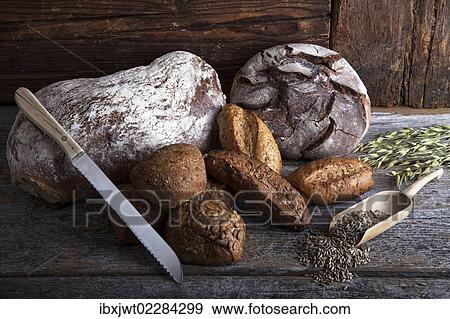 "Bread loaves, rolls and a bread knife, rye grain and ears of corn on a rustic wooden surface" View Large Photo Image Stock Photo - "Bread loaves, rolls and a bread knife, rye grain and ears of corn on a rustic wooden surface". Fotosearch