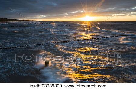 "Breakwaters or groynes, sunset, storm clouds, breaking wave, evening light, Baltic Sea, Fischland-Darss-Zingst peninsula, Mecklenburg-Western Pomerania, Germany, Europe" View Large Photo Image Stock Image - "Breakwaters or groynes, sunset, storm clouds, breaking wave, evening light, Baltic Sea, Fischland-Darss-Zingst peninsula, Mecklenburg-Western Pomerania, Germany, Europe". Fotosearch