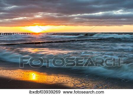 "Breakwaters or groynes, sunset, storm clouds, breaking wave, evening light, Baltic Sea, Fischland-Darss-Zingst peninsula, Mecklenburg-Western Pomerania, Germany, Europe" View Large Photo Image Stock Photo - "Breakwaters or groynes, sunset, storm clouds, breaking wave, evening light, Baltic Sea, Fischland-Darss-Zingst peninsula, Mecklenburg-Western Pomerania, Germany, Europe". Fotosearch