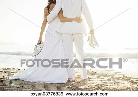 "Bridal couple standing arm in arm on the beach, Spain, Europe" View Large Photo Image Stock Photograph - "Bridal couple standing arm in arm on the beach, Spain, Europe". Fotosearch