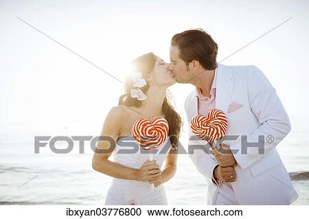 "Bride and groom kissing, heart-shaped lollipops in their hands, Spain, Europe" View Large Photo Image Stock Image - "Bride and groom kissing, heart-shaped lollipops in their hands, Spain, Europe". Fotosearch