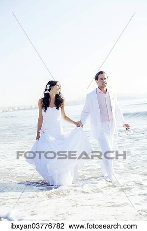 Stock Image - "Bride and groom walking on the beach, Ibiza, Spain, Europe". Fotosearch