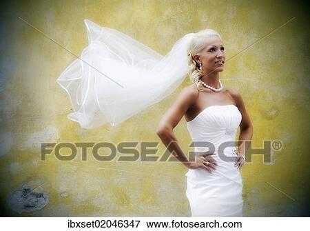 Bride with flowing veil in front of an old yellow wall View Large Photo Image Stock Photo - Bride with flowing veil in front of an old yellow wall. Fotosearch