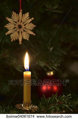 Burning candle in front of a Christmas tree with a star made of straw and a Christmas bauble View Large Photo Image Picture - Burning candle in front of a Christmas tree with a star made of straw and a Christmas bauble. Fotosearch