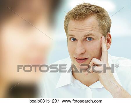 "Business man holding his hand on his cheek, blurred woman in the foreground" View Large Photo Image Stock Photo - "Business man holding his hand on his cheek, blurred woman in the foreground". Fotosearch