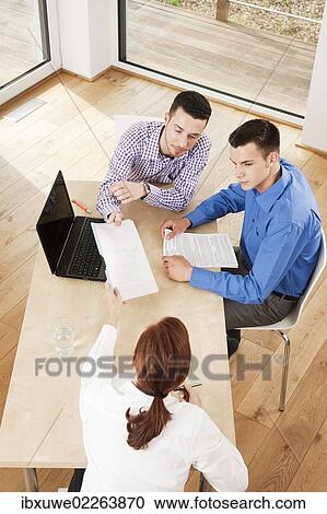 Business team having a meeting around a desk View Large Photo Image Stock Image - Business team having a meeting around a desk. Fotosearch