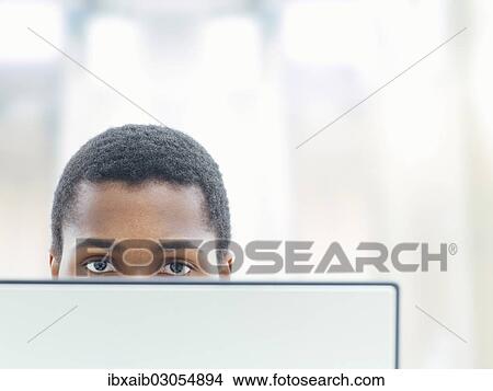 Businessman behind a laptop in an office View Large Photo Image Picture - Businessman behind a laptop in an office. Fotosearch