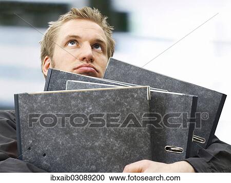 "Businessman carrying ring binders, looking dissatisfied, frustrated" View Large Photo Image Stock Image - "Businessman carrying ring binders, looking dissatisfied, frustrated". Fotosearch