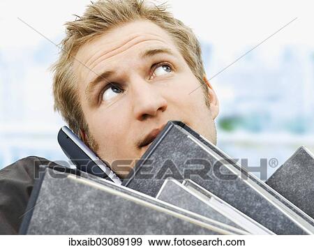 "Businessman carrying ring binders while using a mobile phone, stressed" View Large Photo Image Stock Photo - "Businessman carrying ring binders while using a mobile phone, stressed". Fotosearch